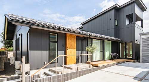 外壁にグレー、玄関扉のみ明るい木材を使用した建物